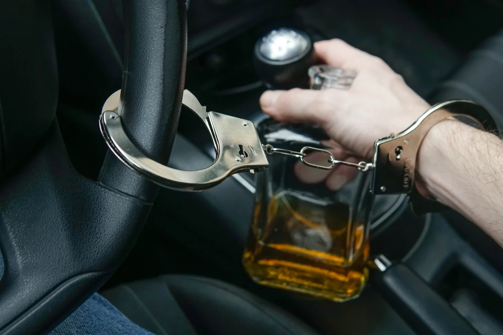man-in-handcuffs-holds-bottle-of-alcohol-in-car-d-2024-10-18-04-11-20-utc